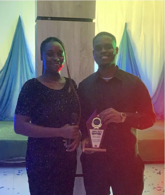 Bright Uzosike holding an award of recognition from the AIESEC in Enugu executive board, beside a colleague